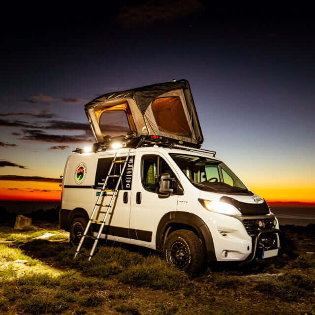 Furgone con tenda da tetto Wild Land aperta e scala appoggiata al tramonto