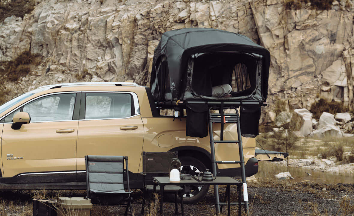 Pick-up con tenda da tetto Wild Land aperta sopra il cassone e campo allestito