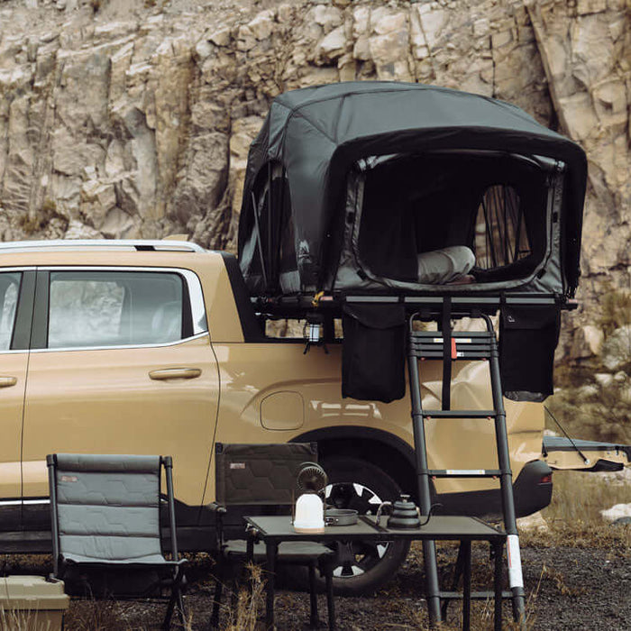Pick-up con tenda da tetto Wild Land aperta sopra il cassone e campo allestito