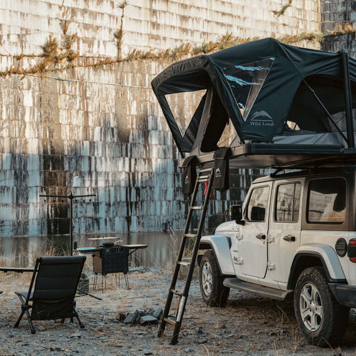 Jeep Wrangler con tenda da tetto Wild Land aperta e campo tra le rocce