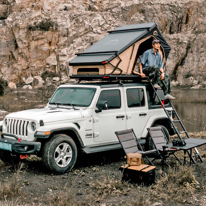 Jeep Wrangler bianca con tenda da tetto Wild Land aperta e campo tra le rocce