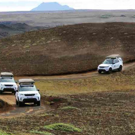 Colonna di SUV Land Rover Discovery con tende da tetto Autohome chiuse su una pista sterrata