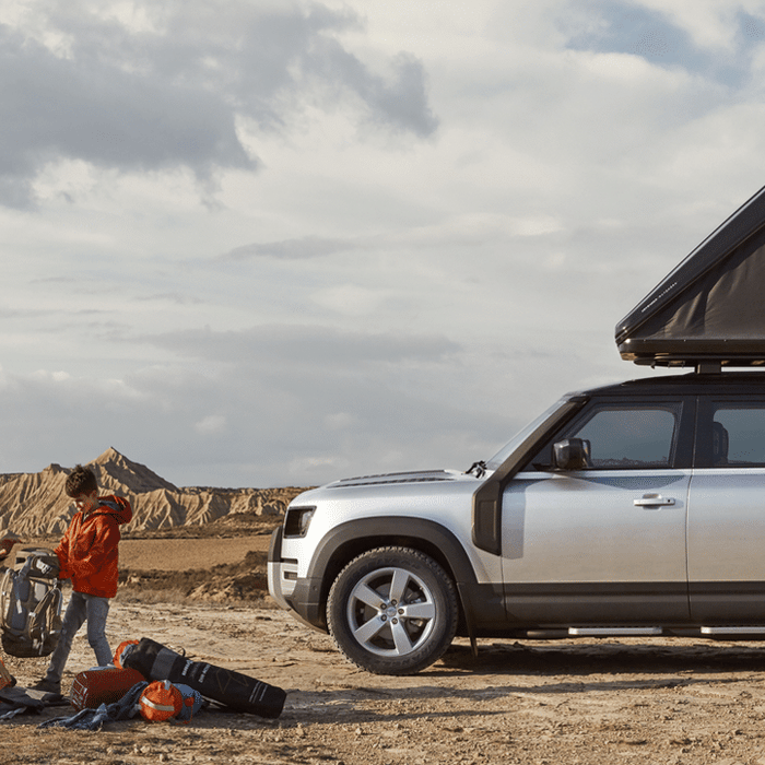 Land Rover Defender con tenda da tetto Autohome aperta e famiglia al campo in un canyon