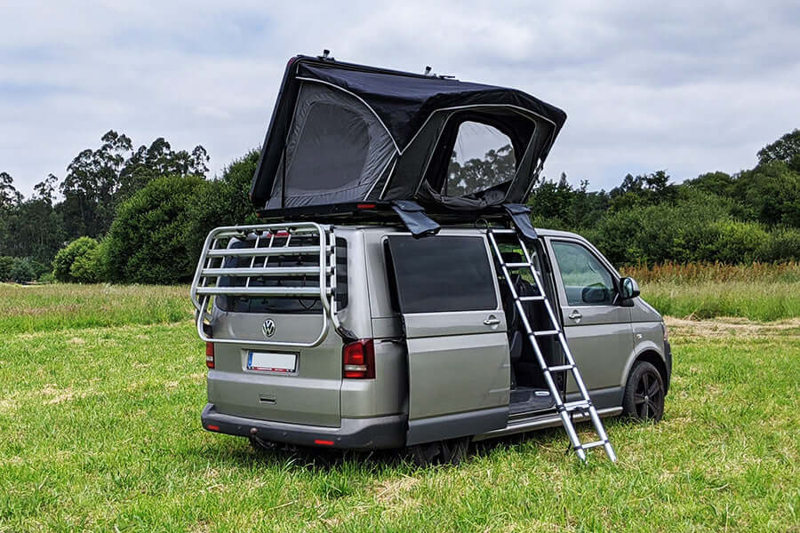 Furgone Volkswagen con tenda da tetto Wild Land aperta su un prato