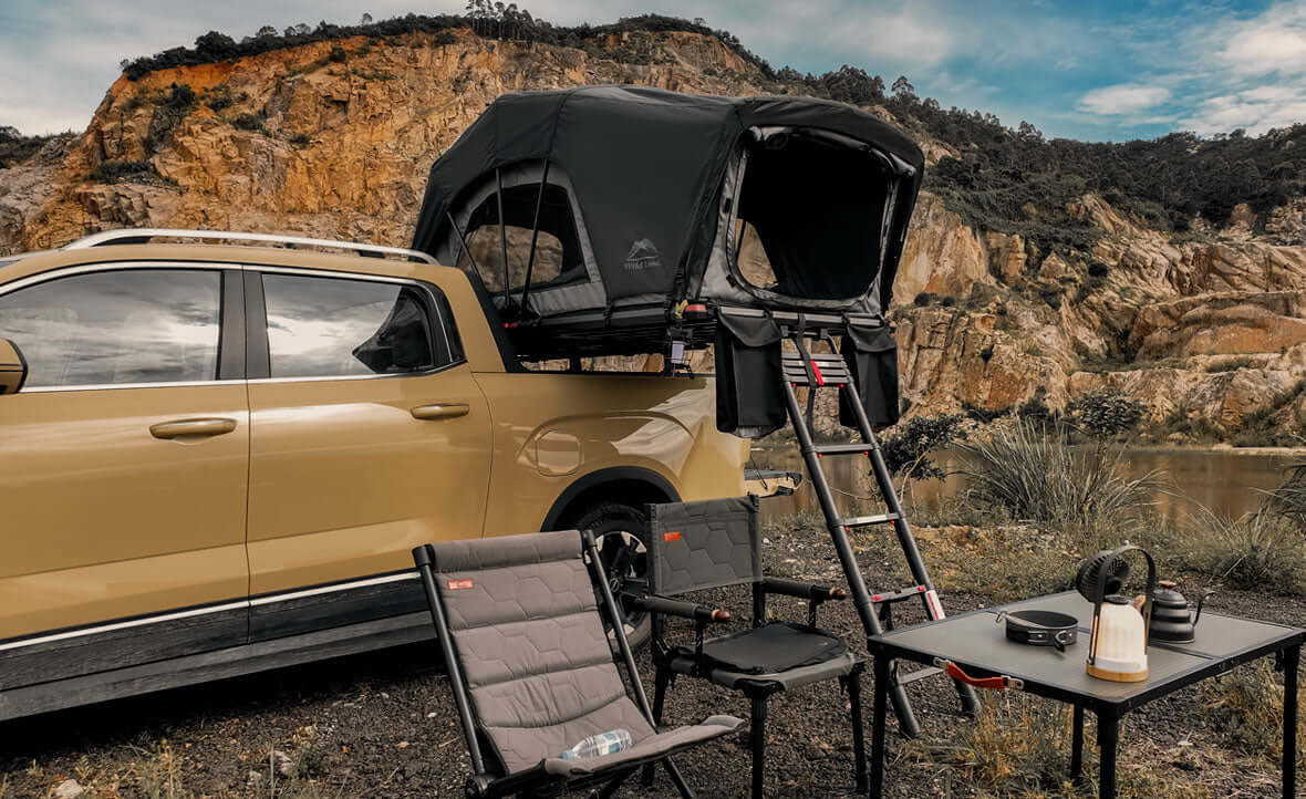 Pick-up con tenda da tetto Wild Land aperta sul cassone e tavolo da campo
