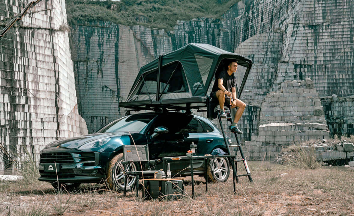 SUV con tenda da tetto Wild Land aperta tra le rocce