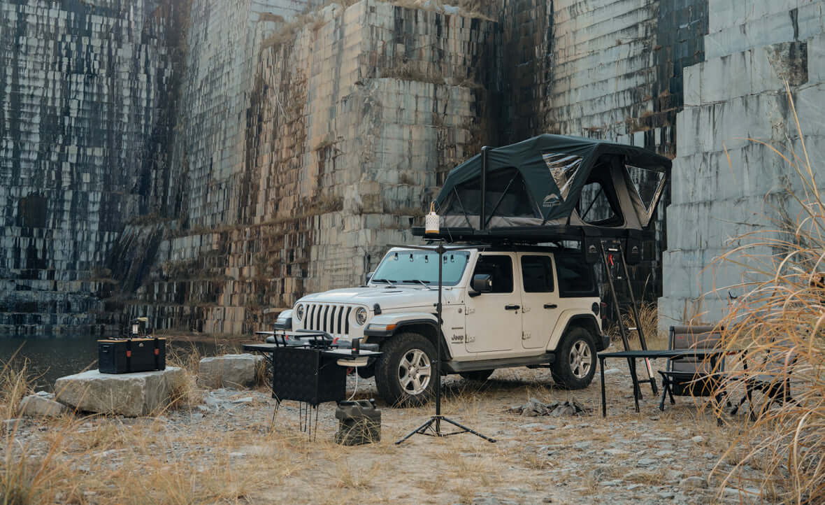 Jeep con tenda da tetto Wild Land aperta e campo allestito in una cava di pietra