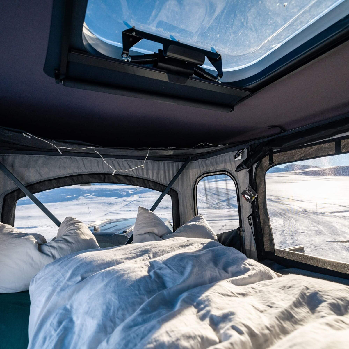 Interno di una tenda da tetto Autohome Air-Sky 360 con vista sulle montagne innevate