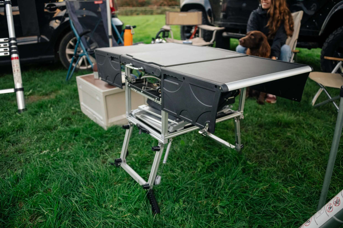 Cucina da campo TentBox aperta con gambe in alluminio su un prato