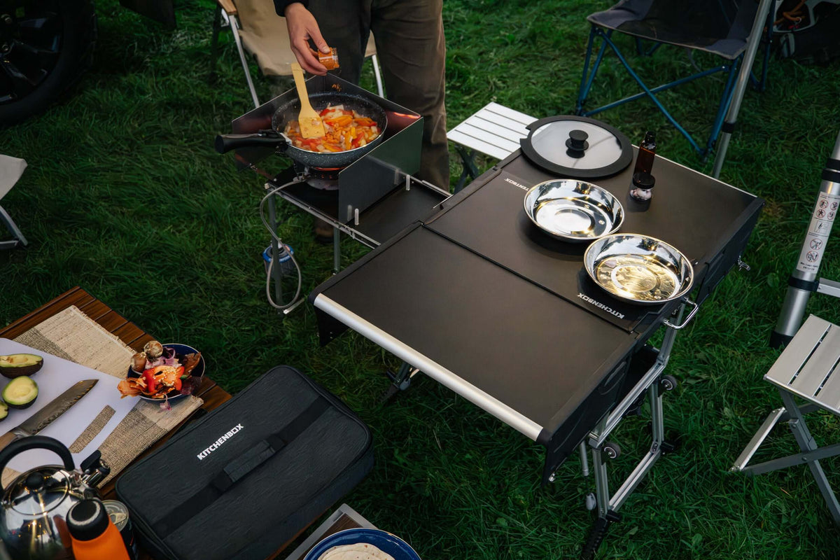 Persone che cucinano su una cucina da campo TentBox su un prato