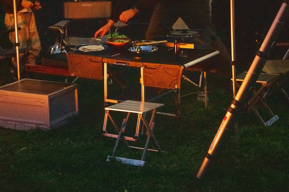 Cucina da campo apparecchiata di sera con sgabelli e luci