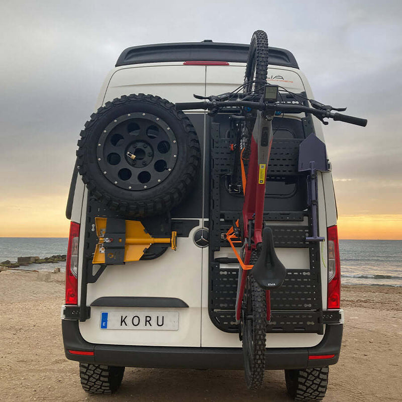 Supporto bicicletta basculante verticale montato su furgone Koru con ruota di scorta.
