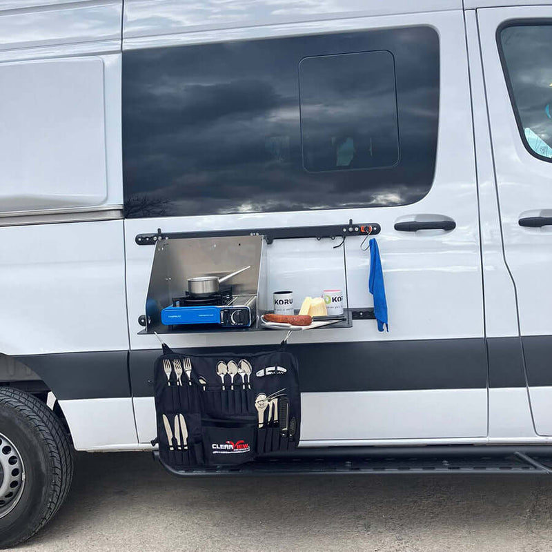 Tavolo laterale porta passeggero installato su furgone con piano cottura e posate.