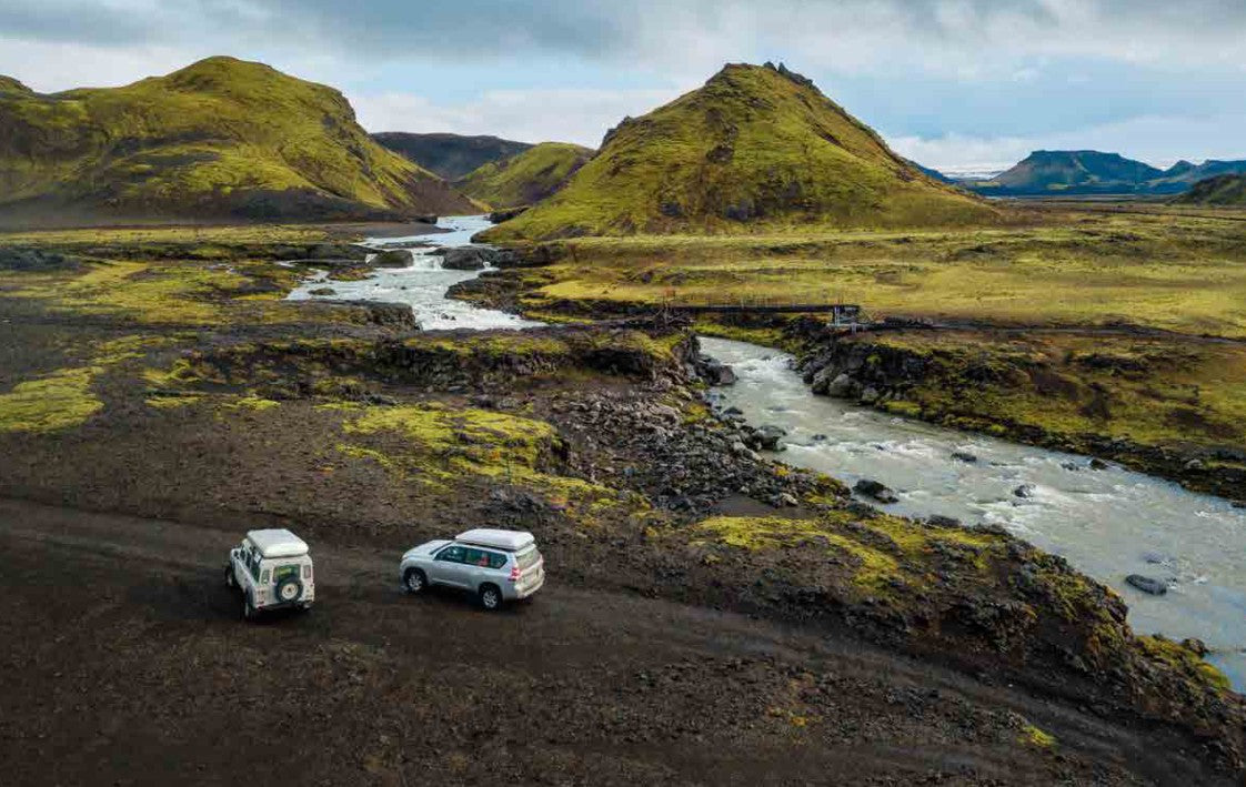 Fuoristrada con tenda da tetto Autohome chiusa lungo un fiume in un paesaggio nordico